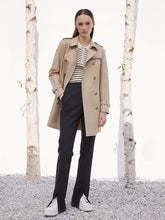 a woman in camel trench coat and black pants